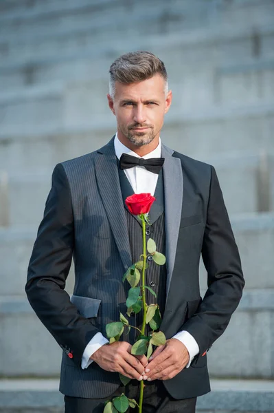 特殊场合的概念 有魅力的男人带着玫瑰迎接特殊的时刻 特定场合的室外燕尾服男 — 图库照片