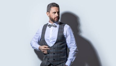 Gri arka planda smokinli karizmatik bir adam. Smokinli adam stüdyoda. Smokin giyen bir adamın fotoğrafı. Erkekler smokin giyer..