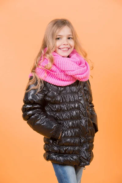 黒いコートとオレンジ色の背景にピンクのスカーフの女の子 長いブロンドの髪を持つ子モデル笑顔 子供の美しさ 秋のファッション スタイル トレンド 幸せな子供時代のコンセプト — ストック写真