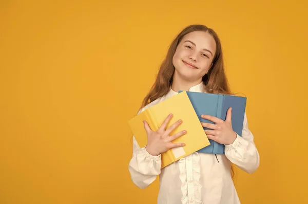 明るい子供は黄色の背景にコピースペースと教育を持つ学校の本を保持します — ストック写真