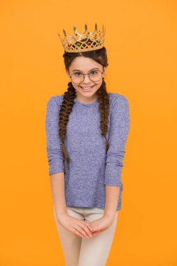 Her zaman gülümseyen prenses. Mutlu prenses sarı arka planı. Prenses kız lüks bir taç takıyor. Küçük prensesin güzel görünüşü. Kuaför salonu. Balo partisi. Moda aksesuarları. Anları ışıldat.