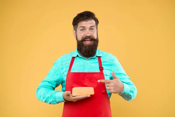 reasonable price and good quality. cheesemaking techniques. cheese maker. hipster with beard in chef apron. Dairy food shop. Online shopping. Gourmet product. happy bearded man hold cheese.