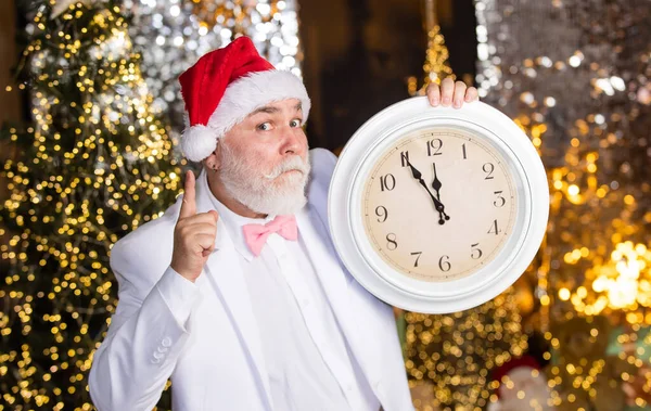 タキシード姿のサンタさん クリスマス サンタは時間を数える 真夜中のコンセプト 新年のカウントダウン レトロな時計の男 ガーランド照明の背景 サンタ ハットで髭を生やしたビジネスマン — ストック写真