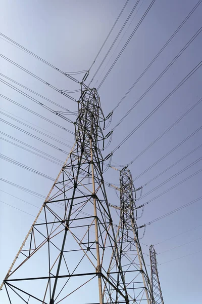 電気塔への電圧伝送 都市を背景にした高電圧 青空を背景に誰もいない強力な変電所 電力線だ パイロンのエネルギー生産 — ストック写真