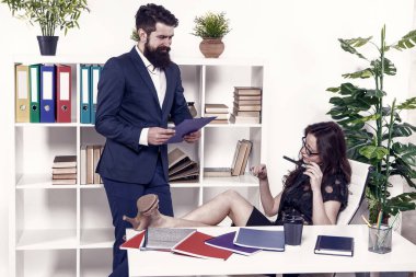 Patron ve çalışan. Kadın egemenliği. Erkek kadına karşı. İş yerindeki iş çifti. Erkek asistan çalışırken kendine güvenen iş kadını rahatlar. İş adamı tembel sekretere talimat verdi.