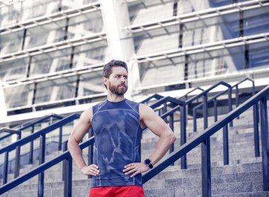 Spor Giysili Adam. Küçük bir mola. Sakallı şehir koşucusu. Spor seansından sonra sakallı sporcu spor sonuçlarını kontrol ediyor. Kronometre özelliği olan dışarıdaki etkinlikler için dijital saat.