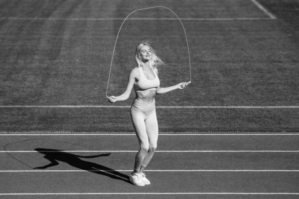 ロープでジャンプする精力的な女性 スキップロープでスポーツウェアジャンプのスポーティーな女の子 スポーツとフィットネス 健康的なライフスタイル 屋外スタジアムでのトレーニング 肉体的訓練 アスレチックレディ — ストック写真