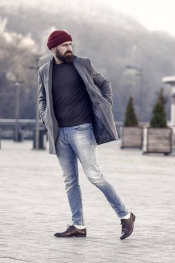 Yürüyüş yenileniyor. Hippi kıyafet ve şapka aksesuar. Şık casual kıyafet bahar mevsimi. Erkek giyim ve erkek moda kavramı. Adam hipster şık moda palto ve şapka sakallı. Rahat kıyafet.