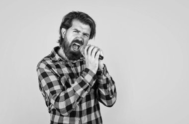 Utangaç olma. Müzik konsepti. Kareli gömlek giyen şarkı söyleyen adam. Karaoke kulübünde kendine güvenen bir erkek şarkıcı. Parti performansı. Sakallı hippi mikrofonda şarkı söylüyor.