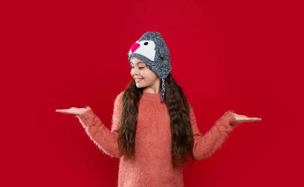 10代の子供のための冬のファッションコピースペースを見てください イヤーフラップ ハット ニットウェア イヤーフラップ ハットの10代の子供モデル 赤い背景に孤立した耳フラップの帽子の10代の子供 スタジオで10代の子供がセーターとイヤーフラップ帽子を着て — ストック写真
