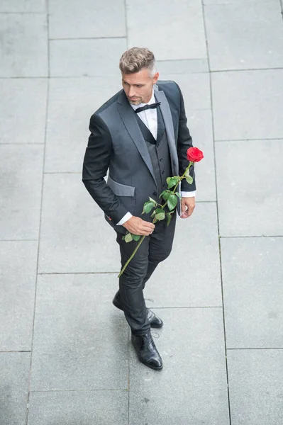 engagement date. tuxedo man celebrates engagement. man with rose gift for engagement outdoor.