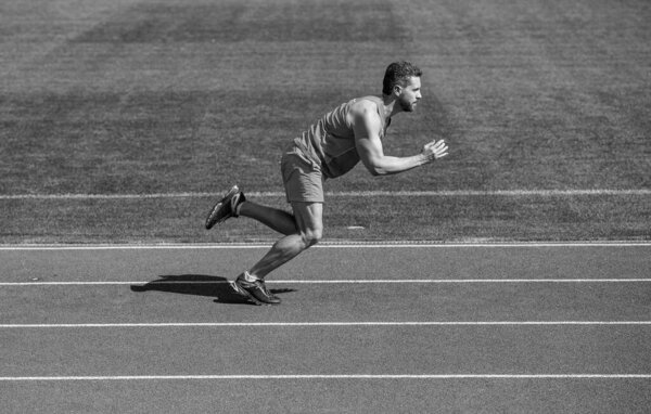 атлетичный мускулистый мужчина бегает в спортивной одежде по стадионной дорожке, финиширует.