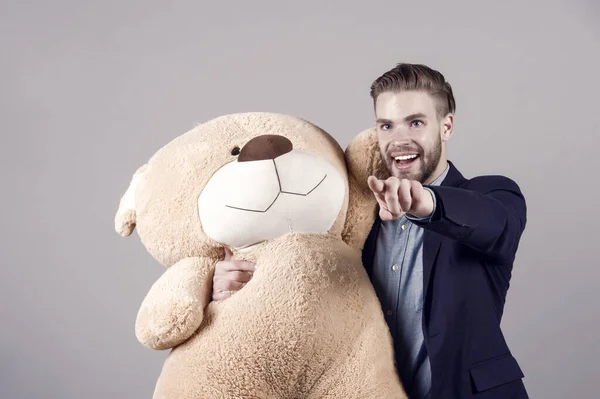 Man in suit hold brown teddy bear on grey background. valentines day