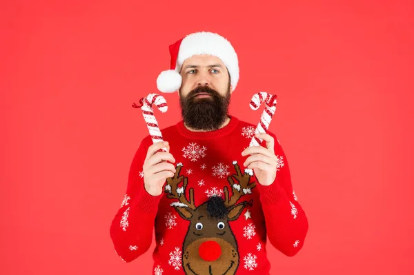 新年快乐 快乐的圣诞节 头戴圣爪帽的大胡子男人 穿着冬季针织圣诞毛衣的野蛮嬉皮士 红底糖果棒的成熟男人 — 图库照片