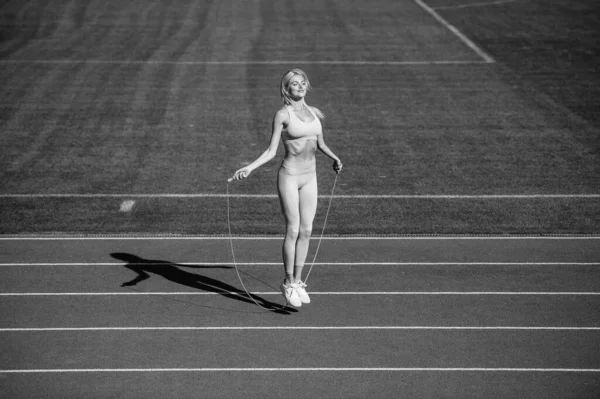 スポーツウェアを着た女性スポーツ選手がフィットネス前に競技場でロープでジャンプし — ストック写真