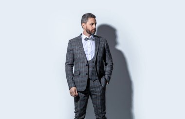 Smokin giyen yakışıklı adamın fotoğrafı. Adam smokin resmi takım elbise giyiyor. Gri arka planda smokinli adam. Stüdyodaki smokin giyen adam..