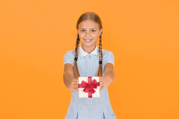 Happy birthday. Knowledge day. Schoolgirl giving gift to you. Tidy adorable pupil open gift box. Educational program for gifted kids. Generosity concept. Holiday celebration. Girl received gift.