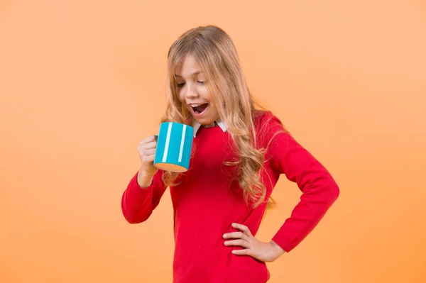 Ребенок Удивленным Лицом Держит Синюю Чашку Оранжевом Фоне Перерыв Чай — стоковое фото