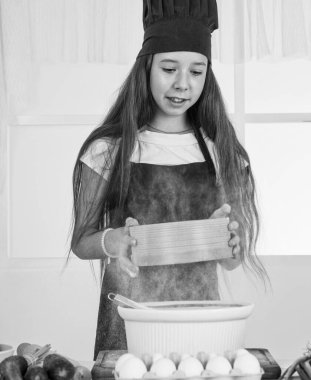 Diyet yapıyorum. Genç fırıncı çocuk mutfakta yemek hazırlıyor. Akşam yemeği için yemek pişirmek. Mutlu çocukluk gelişimi. Çocuk aşçı üniforması giyiyor. Sadece sağlıklı ürünler kullanın. Vitamin dolu. Yiyeceklerle oynamak..