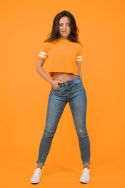 Güzellik ve makyaj. Uzun saçlı güzel bir kız. Moda ve tarz. Dar kot ona yakışıyor. Kendine güven en iyi ekiptir. Seksi kız sarı arka plan. Seksi bir kız. Sıradan tarzda şehvetli bir kız..