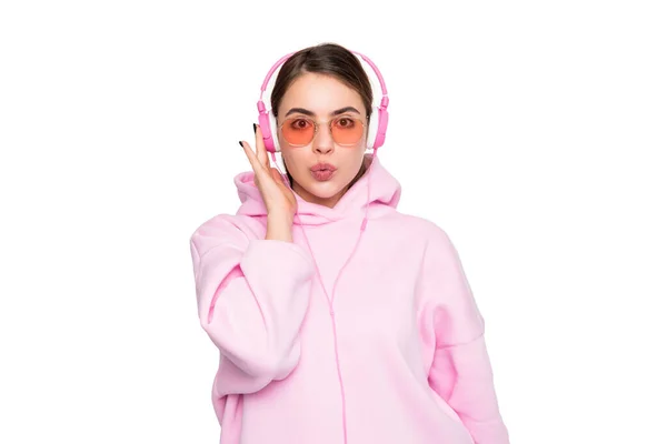 戴着休闲粉色帽及眼镜的女孩 戴着耳机听着音乐 嘴唇被白色隔离 — 图库照片
