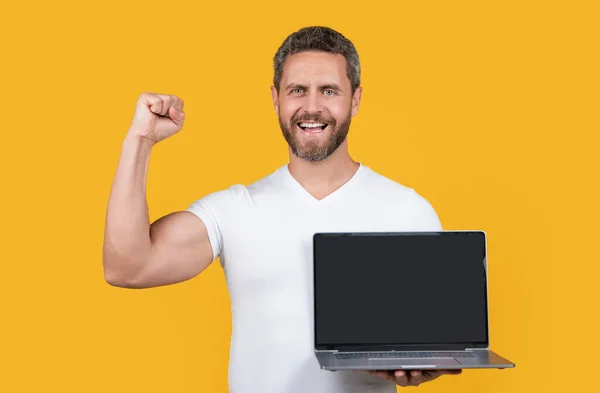スタジオでノートパソコンのアプリを見せる幸せな男 ノートパソコンでアプリを見せる男 コピースペースでアプリを見せる男 黄色の背景にアプリを表示する男は — ストック写真