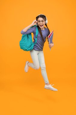 Şüphe götürmez bir çocukluk. Havada sarı arka planda mutlu bir çocuk. Küçük kız okula geri döndü. Okul zamanı. Çocukluk gelişimi ve eğitim. Çocukluk aktivitesi. Gelecek için çocukluk hayali.