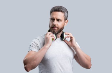 Yakışıklı adam stüdyoda kulaklıkla müzik dinliyor. Modern kulaklıkla müzik dinleyen bir adam. Kulaklıkla müzik dinleyen bir adamın fotoğrafı. Gri kulaklıkla müzik dinleyen adam izole edilmiş.