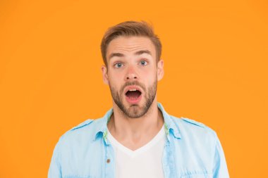 Bu ne sürpriz. Erkek yaz modası. Şaşırmış adamın sarı arka planda saçları var. İnsani duygular. Havalı saç stili olan seksi çocuk tişört giyiyor. Tıraşsız, yakışıklı, kıllı adam..