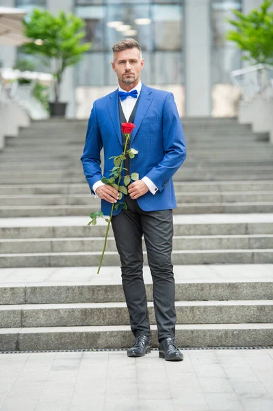 elegant man in tuxedo at romantic occasion. man with romantic present. luxury romantic man with rose.