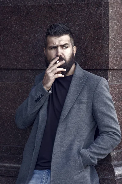 一个凶狠的大胡子男人 留着胡子 穿着时髦的现代休闲装 在户外抽烟 坏习惯 — 图库照片