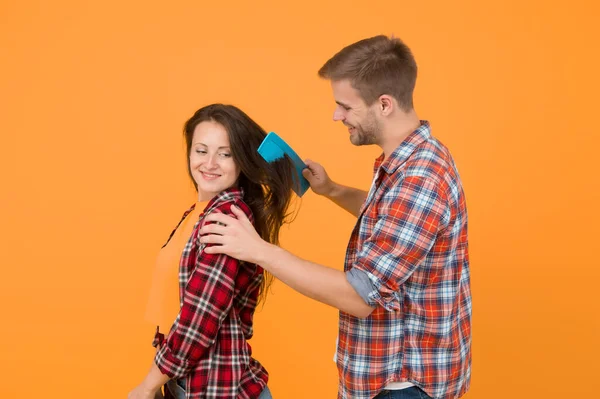 Hair care at home. Helping with hairstyle. Couple having fun with big comb. Combing and brushing hair. Man and woman taking care hair themselves. Hairdresser services. Creative mood. Change hairdo.