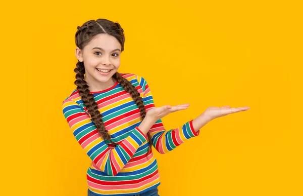儿时工作室拍摄的少女展示产品 童年的概念 孩童时期的辫子女孩在黄色背景下被隔离 在演播室里做辫子的少女的童年 — 图库照片