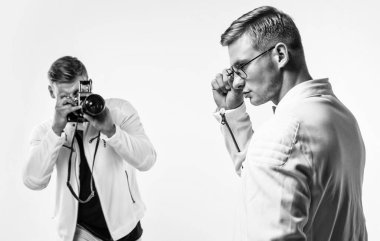 Beyaz elbiseli ikiz kardeş fotoğrafçılar birbirine benzer. Klasik fotoğraf makinesi kullanırlar, fotoğraf çekerler..