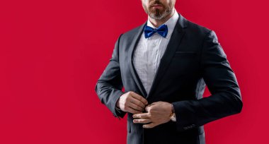 Smokinli adam kırmızı arka planda izole edilmiş, kopyalama alanı. Stüdyoda smokin giyen adam. Smokin giyen bir adamın fotoğrafı. Erkekler smokin giyer..