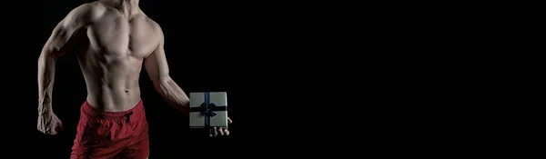 muscular man with gift box. present from man with muscular torso isolated on black. banner of muscular man with gift, copy space. man with muscular torso hold gift.