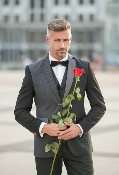 在浪漫的场合穿燕尾服的帅哥 带着浪漫礼物的男人 美丽的浪漫男子与玫瑰 — 图库照片