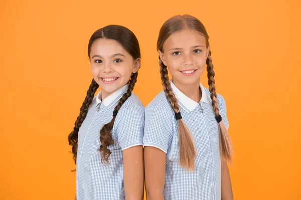 old school fashion. back to school. happy beauty with pigtails. happy childhood. brunette and blond hair. sisterhood concept. best friends. vintage style. small girls in retro uniform. at hairdresser.