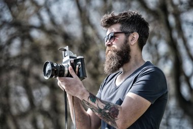 Fotoğrafçı sakal ve bıyık amatör fotoğrafçı doğa arka plan ile. Fotoğraf çekimi ile meşgul uzun sakallı adam. Fotoğrafçı kavramı. Adam sakallı hippi fotoğrafçı tutun vintage fotoğraf makinesi.