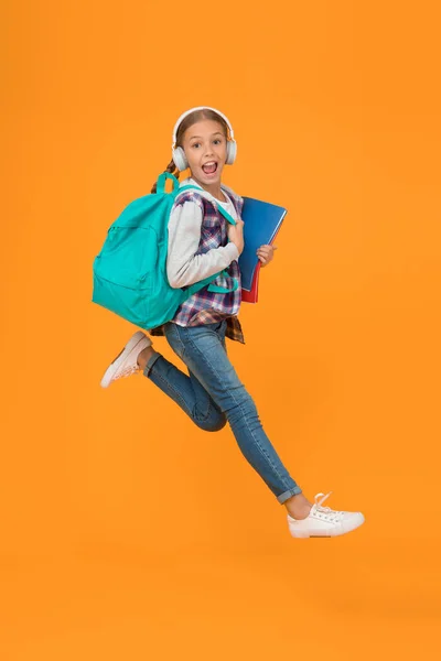 重新开始学习 精力充沛的小女孩奔向学校的黄色背景 带着书包和书回到课堂的小孩 回学校去吧 欢迎回来 — 图库照片