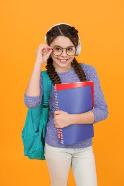 Ses kütüphanesi. Mutlu çocuk kütüphane kitaplarını tutuyor. Küçük kız kütüphaneye gidiyor. Okul kütüphanesi. Kitap ve edebiyat. Bilgi toplama günü. Bibliopol. Eğitim. Ses dili kursu. Dinliyor ve konuşuyor..