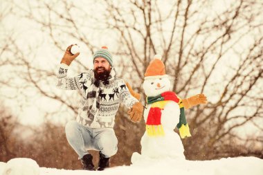 Kardan adam konsepti. Sakallı hippi yakışıklı örgü şapka dışarıda karla oynuyor. Soğuk kış gününüzde iyi eğlenceler. Kar yağsın. Noel tatili. Aktif yaşam tarzı. Kar oyunları. Temiz havada vakit geçirmek..