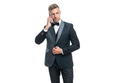 Smokinli iş adamı, beyaz arka planda izole edilmiş akıllı telefondan konuşuyor..