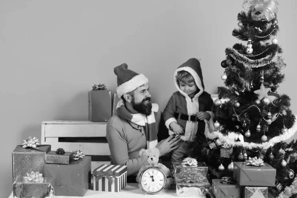 长胡子 面带笑容的男孩和男子把圣诞球放在树上 圣诞老人和小助手在礼品盒里圣诞家庭在粉红色的背景上装饰冷杉树 寒假和装修概念 — 图库照片