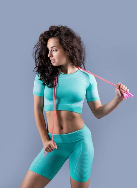 fitness woman in sportswear with skipping rope at studio. fitness woman in sportswear hold skipping rope isolated on grey background. fitness and sport.