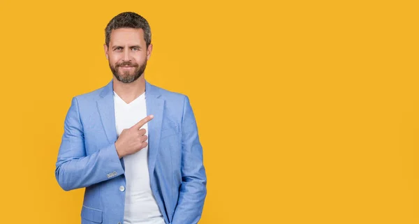 stock image businessman wearing formal jacket directing. caucasian businessman in jacket isolated on yellow background. businessman in studio. photo of handsome businessman wear suit.