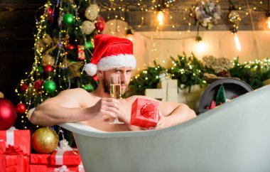 Sıcak banyo. Sıcak banyo sağlık yararları. Noel Baba sıcak banyoda lüks içinde. Keyfini çıkar. Kendimi şımartıyorum. Kış tatili Noel konsepti. Küvette yatan adam hediye kutusuyla rahatlar. Spa ve sağlık.