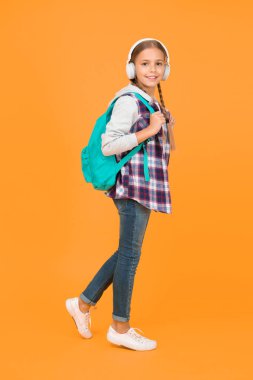 Enerjik neşeli genç müzik dinliyor. Şık liseli kız okula gidiyor. Sırt çantalı, şık bir kız. Okul hayatı. Mutlu tasasız çocuk. Okul dersleri. Öğrenci. Modern eğitim.