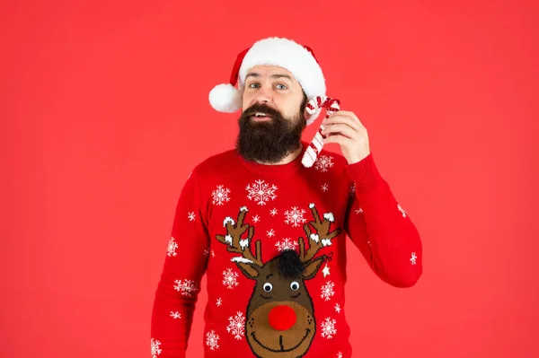 一个留着胡子 头戴圣诞帽 头戴毛衣的人 拿着红底棒棒糖 — 图库照片