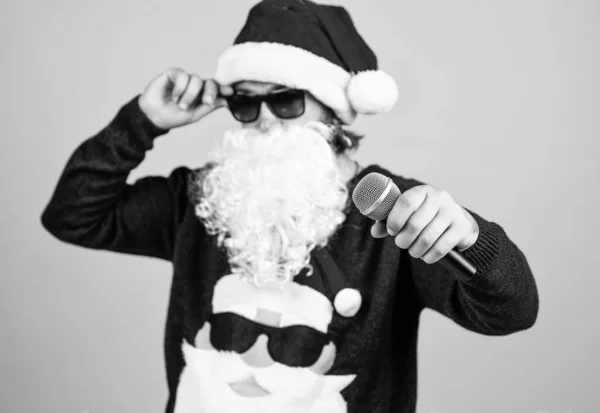 Congratulating his nearest. christmas songs. xmas shopping time. prepare gifts and presents. karaoke. happy bearded man in santa hat sing in microphone. new year party. celebrate winter holidays.